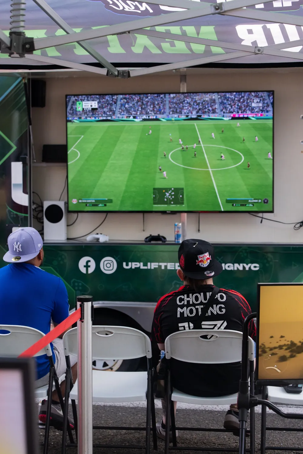 Adults playing FIFA on the outdoor screen of the Uplifted Gaming NYC trailer