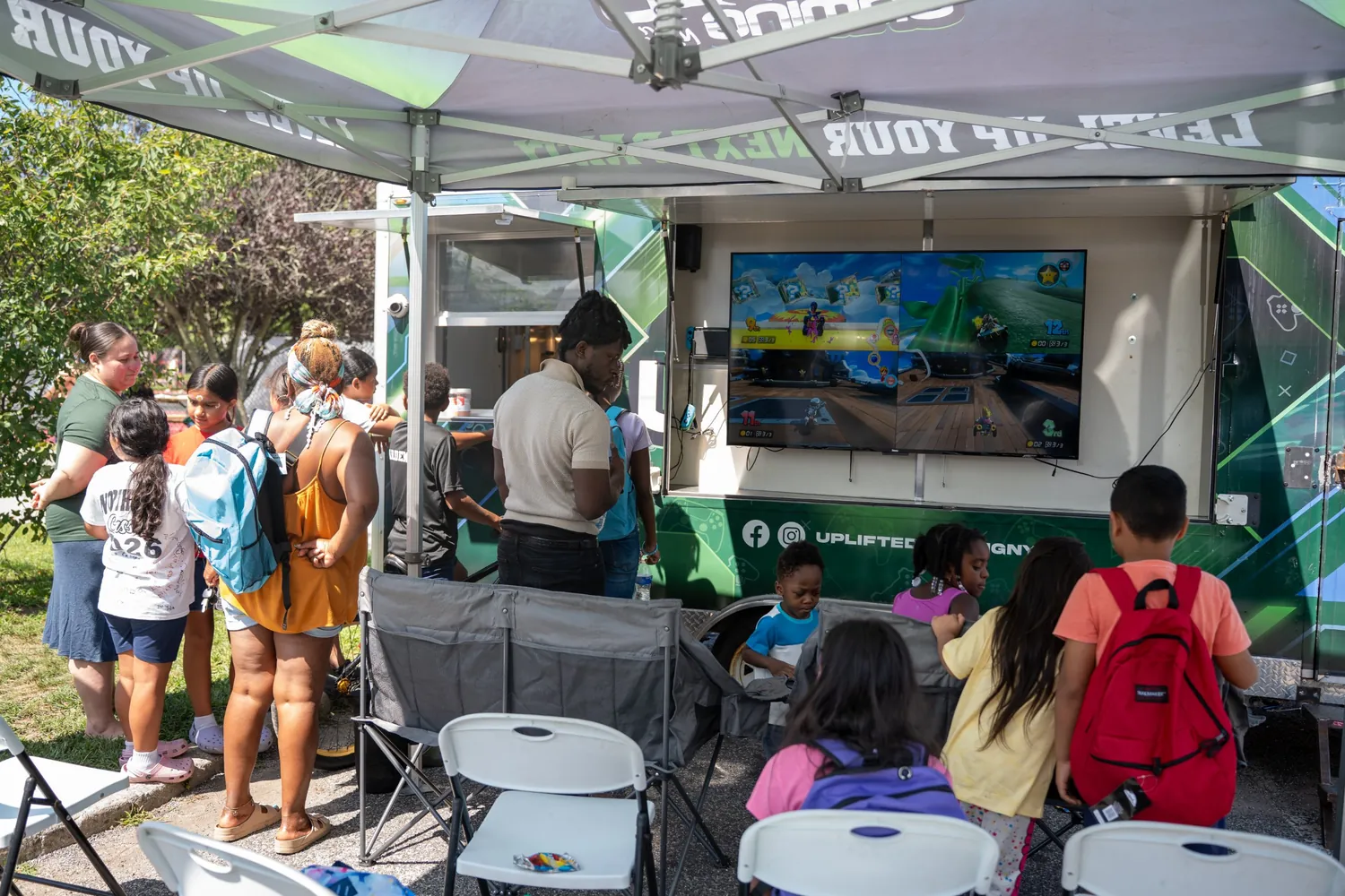 Kids and parents playing Mario Kart on the trailer's outdoor screen at an NYC block party