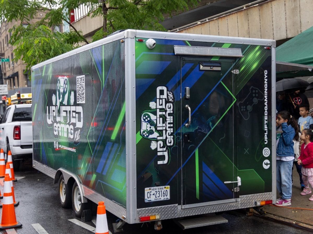 The Uplifted Gaming NYC mobile gaming trailer parked at a street event with kids lining up to play
